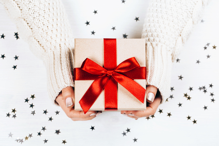 Female hands holding present with red bowの写真素材
