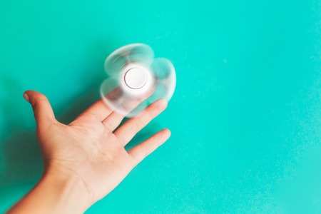 Fidget spinner, spinning in hand on trendy pastel blue background.の写真素材