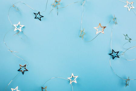 Golden star shaped garland on pastel blue background. Flat lay style. Christmas concept.の写真素材