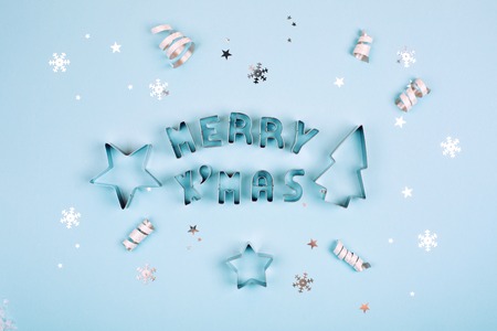 Merry Christmas text with sparkles and shapes for gingerbread on blue pastel background. Flat lay style. Concept of celebrating new year. Christmas mood.の写真素材