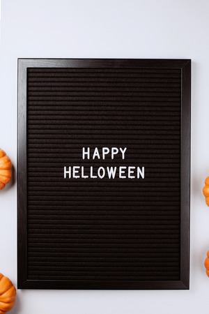Happy Halloween words on black letter textured board. It is in frame with small yellow pumpkins. Flat lay style.の写真素材