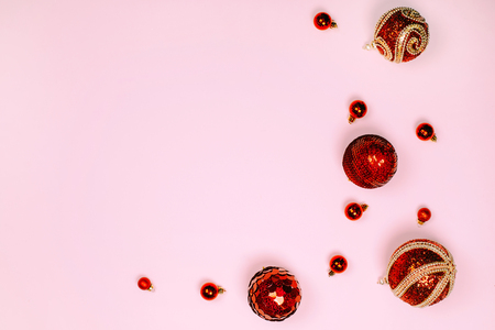 Red christmas balls are creating frame on pink pastel background. Place for text. Festive concept.の写真素材