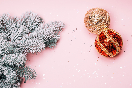 Christmas snowy fir-tree and two textured baubles on pink pastel background. Place for text. Festive concept.の写真素材