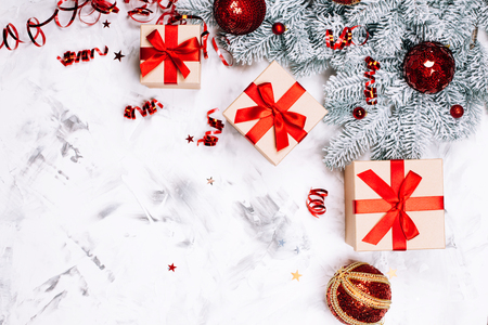 Three present boxes with red bow, christmas balls and snow fir-tree on white concrete background. Place for text. Festive concept.の写真素材