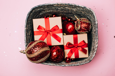 Silver box with presents and red christmas balls on pink pastel background. Flat lay. New year concept.の写真素材