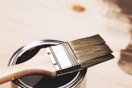 Paintbrush and a newly opened can of grey paint on wooden surfaceの写真素材