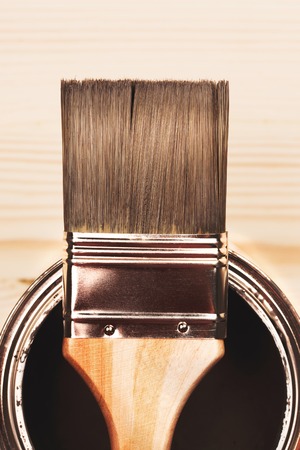 Paintbrush and a newly opened can of grey paint on wooden surfaceの写真素材