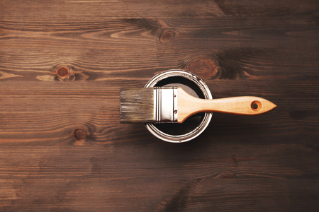 Paintbrush and a newly opened can of grey paint on fresh painted wooden surfaceの写真素材
