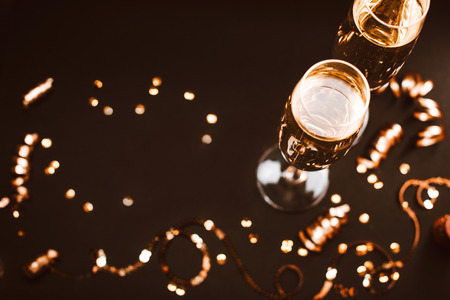 Two glasses of champagne with golden decoration on black elegant background. Top view, place for text. Festive concept.の写真素材