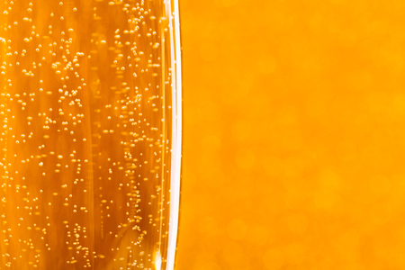 One glass of champagne on golden blurred background. Macro, place for text. Festive concept.の写真素材