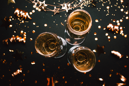 Three glasses of champagne on holiday black background with golden decoration. Top view. Festive concept.の写真素材