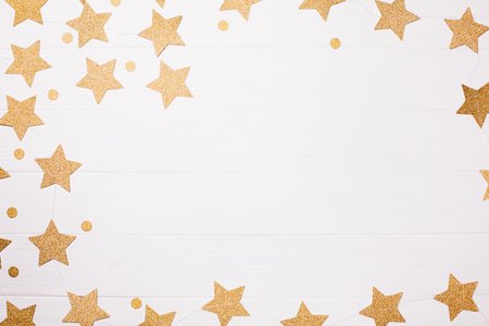 Golden decoration of stars and circles is creating frame on white wooden background. Place for text.の写真素材