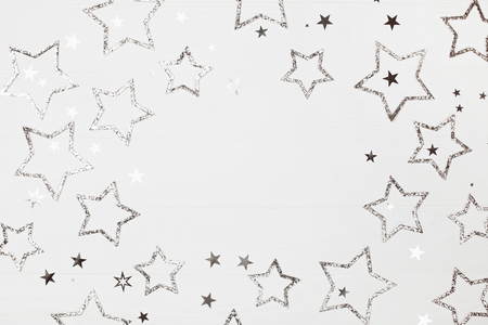 Holiday background of silver stars with sparkles on white wooden background. Place for text. New Year concept.の写真素材