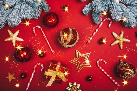 Beautiful sparkling Christmas decorative toys with caramel candies on red background. Flat lay style. Festive concept.の写真素材