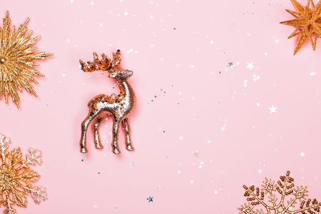 Golden christmas decotartive deer with some glittering snowflakes on pink pastel background. Festive concept.の写真素材