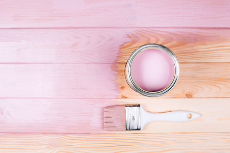 Open can of pink paint with white brush on painting wooden board. Renovation concept.の写真素材