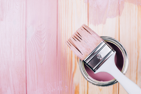 White brush on open can of pink color on painting wooden board. Renovation concept. Place for text.の写真素材