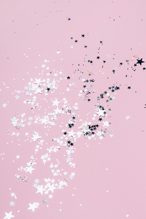 Silver sparkles, stars and glitters on pink background. Festive concept.の写真素材