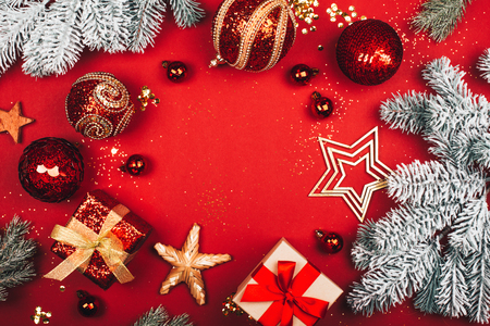 Sparkling Christmas decorative toys create round frame on red background. Flat lay style. Festive concept.の写真素材