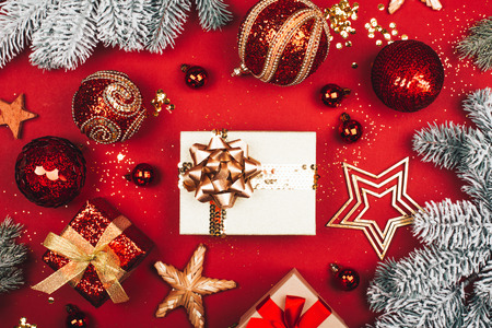 Many presents among sparkling Christmas decorations on red background. Flat lay style. Festive concept.の写真素材