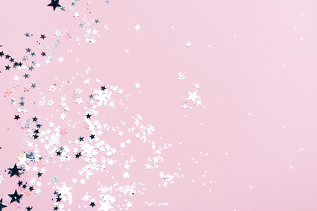 Silver sparkles, stars and glitters on pink background. Festive concept.の写真素材