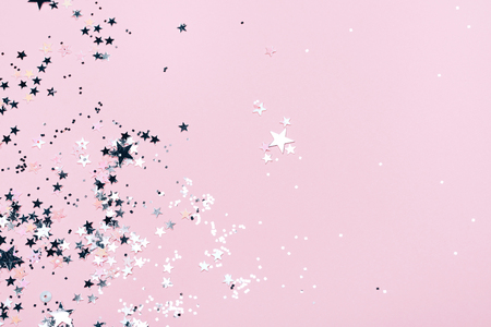 Silver sparkles, stars and glitters on pink background. Festive concept.の写真素材