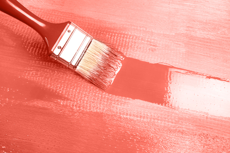 Varnishing a wooden shelf using paintbrush, Living Coral Color of the Year 2019. Main trend concept.の写真素材