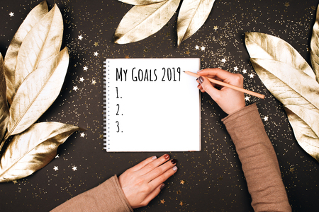 Goal lift for New Year. Holiday decorations and notebook with wish list on dark table, flat lay style. Planning concept.の写真素材