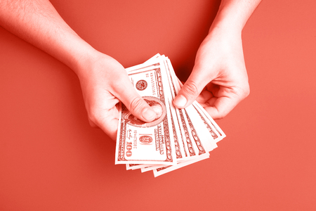 Man counting money on Living Coral background. Concept of color of the year.の写真素材