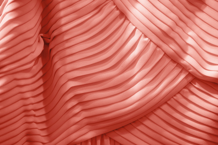 Living Coral background of luxury dress with wavy folds. Festive concept.