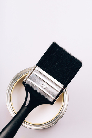 Brush with black handle on open can of white paint on grey background. Renovation concept. Top view.の写真素材