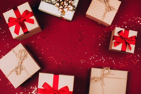 Many Christmas craft presents with glitter create round frame on red background. Festive concept. Top view.の写真素材