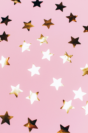 Many beautiful golden stars on pink background. Flat lay style.の写真素材