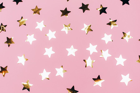 Many beautiful golden stars on pink background. Flat lay style.の写真素材