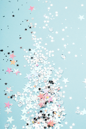 Star shaped form with holographic and silver glitter on blue pastel background. Festive concept. Place for text.の写真素材
