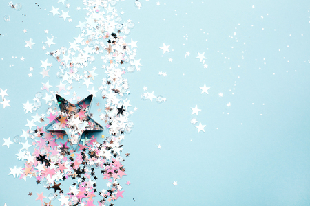 Star shaped form with holographic and silver glitter on blue pastel background. Festive concept. Place for text.の写真素材