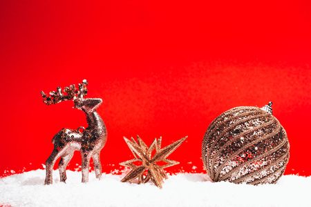 Christmas golden decorative toys on red background with snow. Festive concept.の写真素材