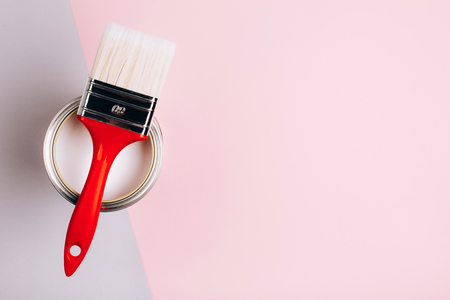 Brush with red handle on open can with pink color of paint on pastel background. Place for text. Renovation concept.の写真素材
