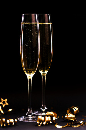 Two glasses of champagne full size with golden ribbon on black stylish background. Christmas coming concept.の写真素材
