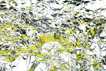 Abstract background made of crumpled foil with yellow color. Ideal backdrop for your design.