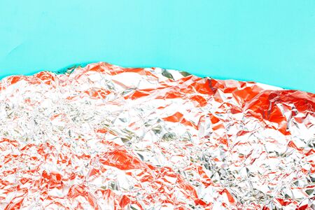 Abstract background made of crumpled foil with coral color on teal backdrop. Place for text.の写真素材