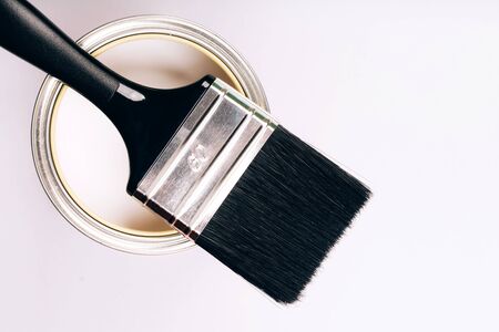 Brush with black handle on open can of white paint on grey background. Renovation concept. Top view.の写真素材