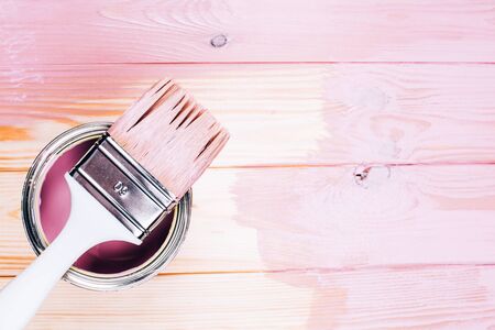 White brush on open can of pink color on painting wooden board. Renovation concept. Place for text.の写真素材