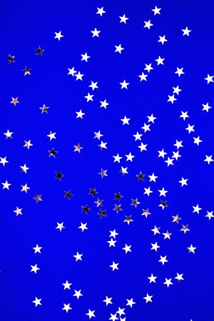Silver stars glitter on blue background. Festive holiday pastel backdrop.の写真素材