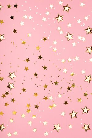 Golden stars glitter on pink background. Festive holiday pastel backdrop.の写真素材