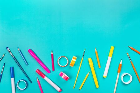 School items as a frame on blue background. Trendy colors, flat lay style. Back to school concept.の写真素材