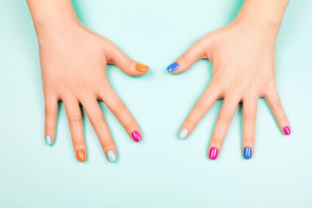 Womans hands with perfect manicure in trendy neon colors on turquoise background. Beauty concept.の写真素材