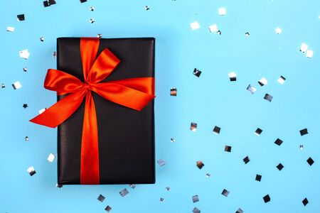 Black gift box with red ribbon on blue background. Black friday sale concept.の写真素材