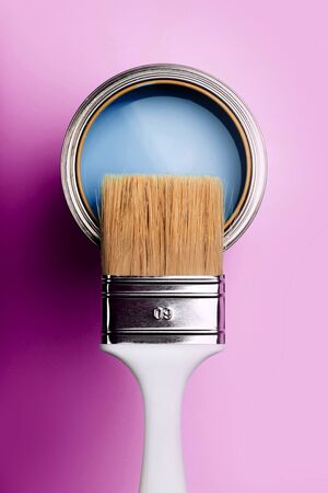 Brush with white handle on open can of turquoise paint on blue pastel background. Renovation concept. Macro.の写真素材