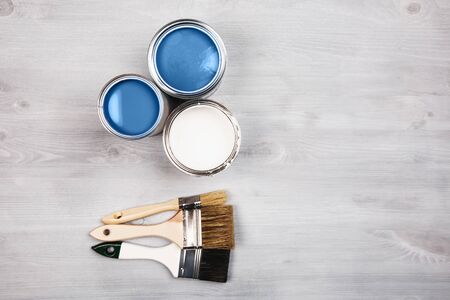 House renovation, paint cans and colored brushes on white wooden background. Blue color of paint.の写真素材
